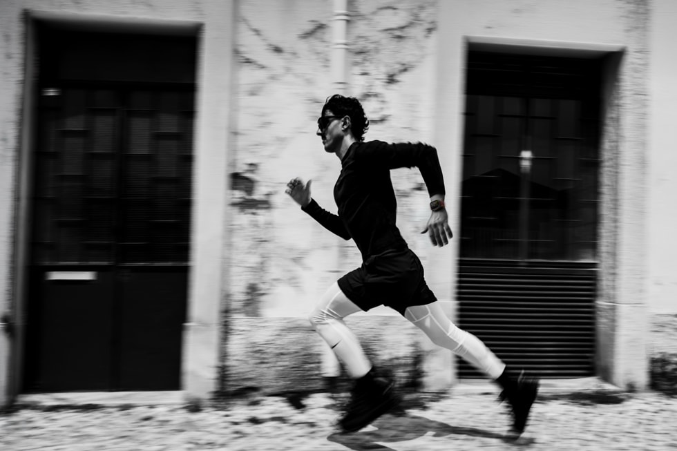 Fotografía en blanco y negro de un corredor que lleva puesto un Apple Watch Ultra 4 mientras corre al aire libre.